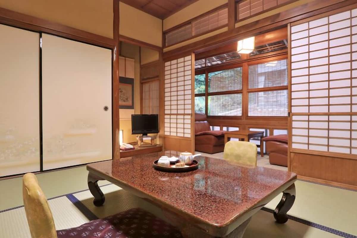Una habitación tradicional japonesa con suelo de tatami, una mesa baja con una bandeja de té y puertas correderas.