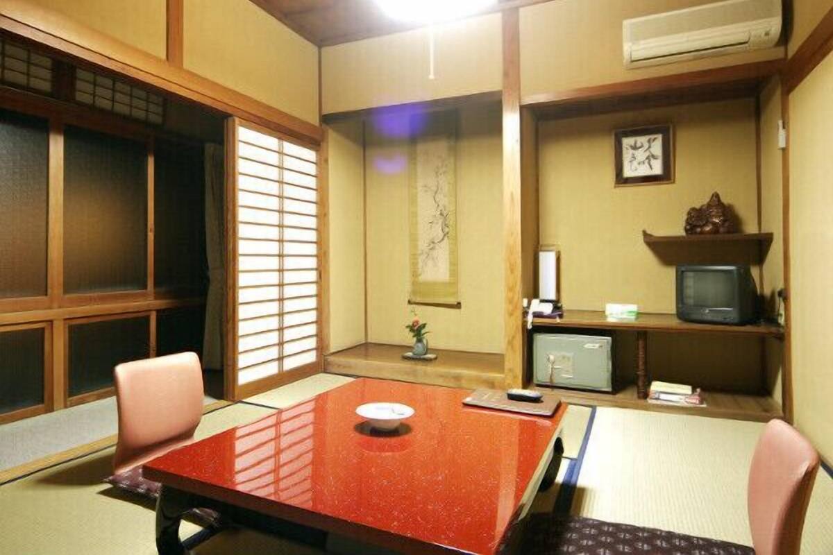 Une pièce de style japonais traditionnel, avec un sol recouvert de tatamis, une table basse et un téléviseur posé sur une étagère.