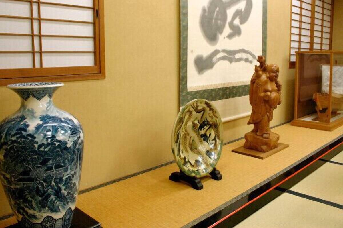 Une exposition d’art japonais traditionnel comprenant un vase en céramique, une sculpture réfléchissante et une œuvre d’art encadrée.