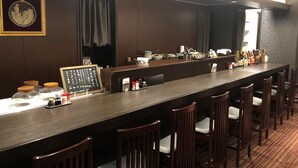 A bar area with a long counter, multiple chairs, and a chalkboard menu. - Grand Plaza Nakatsu Hotel (Nakatsu)