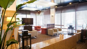 A modern lobby with a large flat-screen TV, comfortable seating, and large windows with blinds. - Grand Plaza Nakatsu Hotel (Nakatsu)