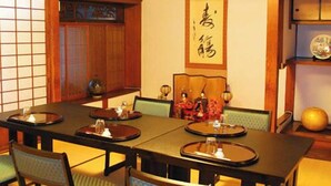Ett traditionellt japanskt matsalsrum med tatamimattor, ett lågt bord och gröna, vadderade stolar.