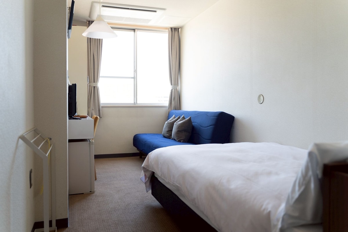 A hotel room with a bed, a desk, and a chair.