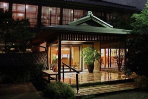A traditional Japanese-style building with a covered entrance, a wooden porch, and a large potted plant. - Akebono (Saga)