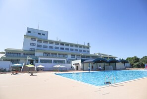 Hotellissa on uima-allas, ulkotila, jossa on istuimia, ja suuri rakennus, jossa on useita ikkunoita.