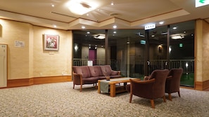 A hotel lobby with a sofa set, a small table, and a glass partition.