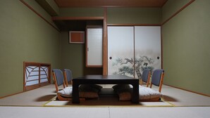 Een kamer met tatami matten, een lage tafel en vier stoelen, een shoji-scherm met een afbeelding van een boom en een schuifdeur.