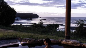 Une personne dans une piscine, avec vue sur une étendue d’eau et une côte lointaine.