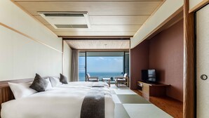 Une chambre d’hôtel avec un grand lit, une télévision et une vue sur l’océan.