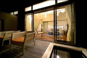 A room with a sliding glass door leading to a balcony with wicker furniture and a view of the interior. - Okuyado Buaisou (Yufu)