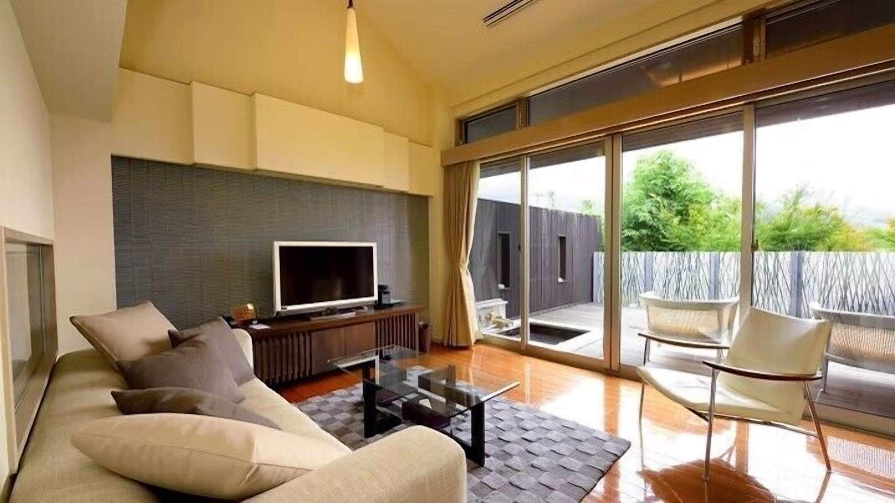 A modern living room with a sofa, TV, and a glass table.