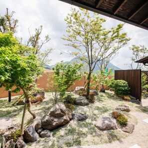 A landscaped garden with rocks, trees, and a wooden structure. - Okuyado Buaisou (Yufu)