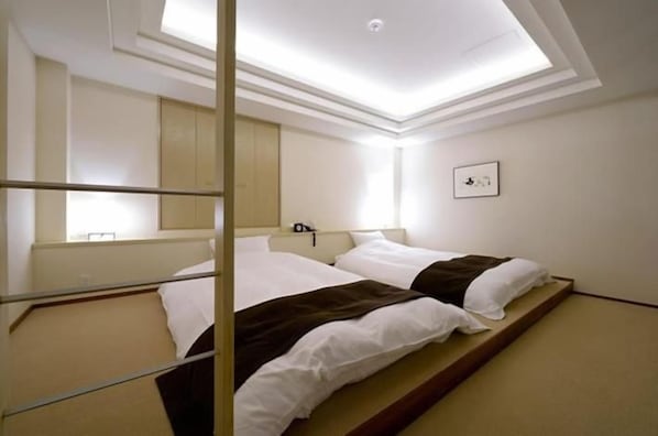 A hotel room with a bed, a bedside table, a mirror, and a ceiling light.