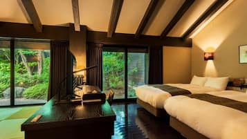 A hotel room with a large bed, a desk, and a view of greenery through the windows.