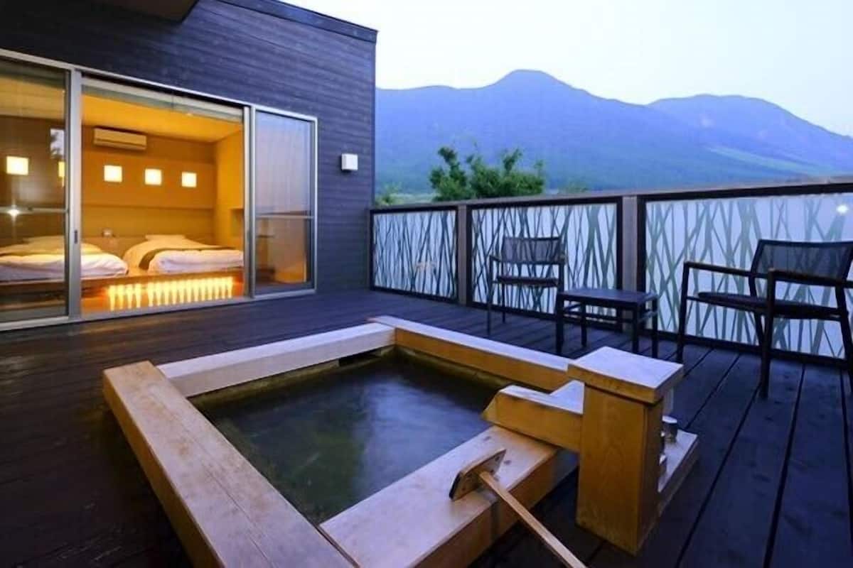 Une chambre d’hôtel moderne dotée d’une grande porte-fenêtre coulissante, d’un jacuzzi et offrant une vue sur les montagnes.