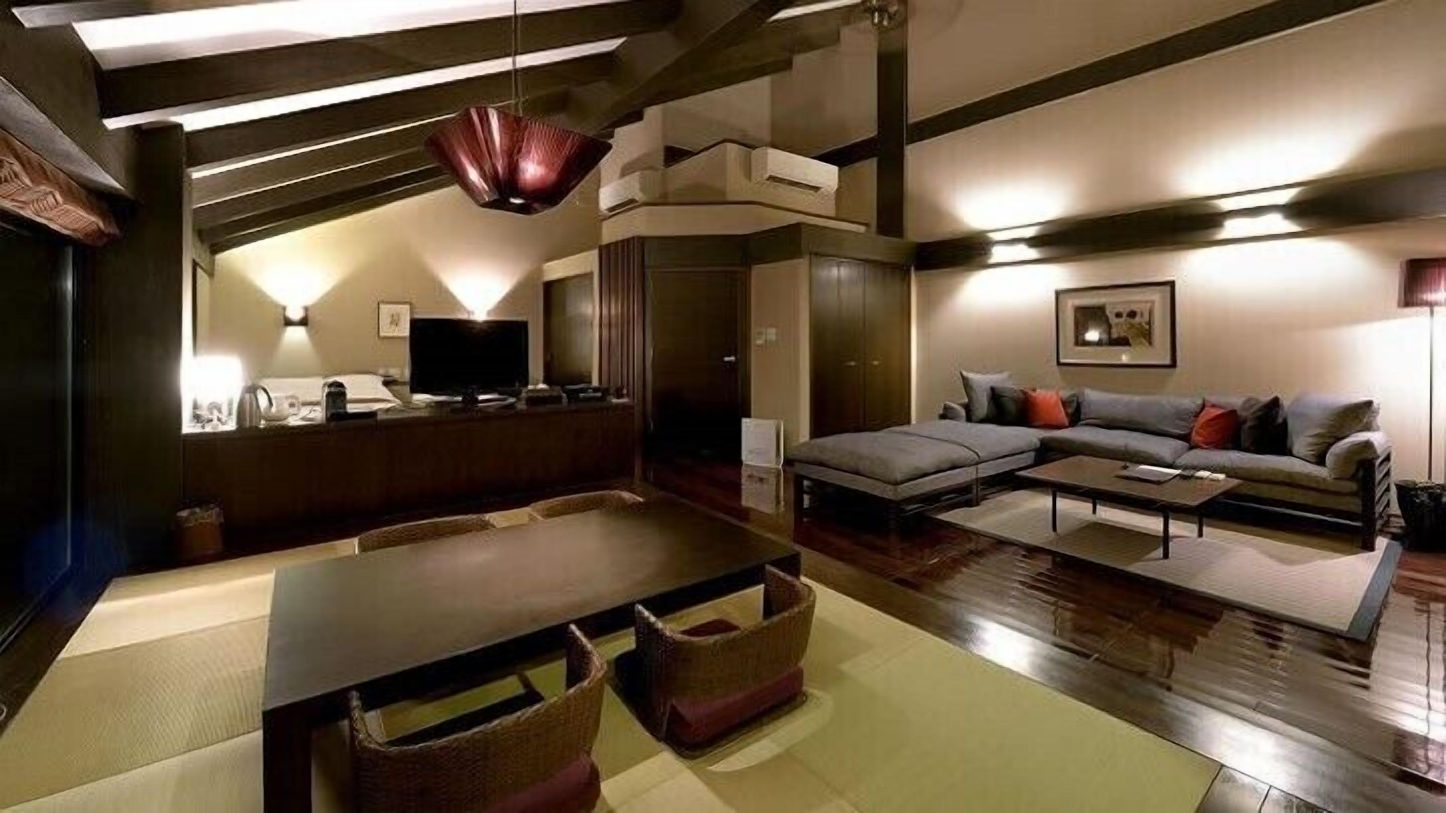 A modern living room with a sofa, coffee table, and a dining area with a table and chairs.
