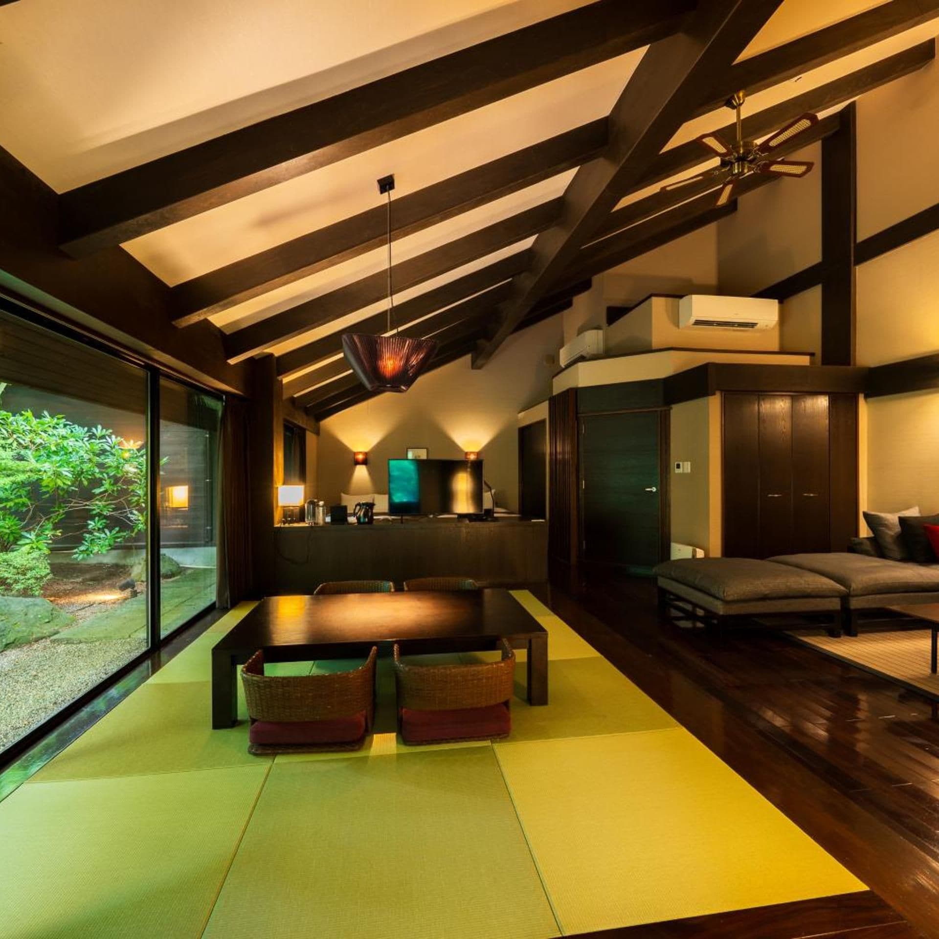 A modern interior with a dining area, seating, and a view of greenery.
