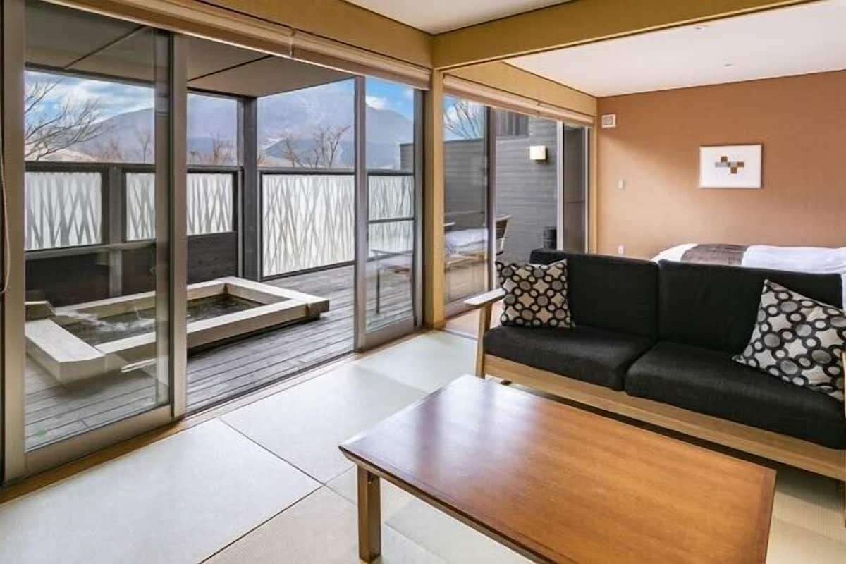 Un salon moderne avec un canapé, une table basse et des portes-fenêtres coulissantes donnant sur un balcon.