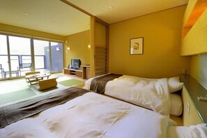 Een hotelkamer met twee bedden, een televisie, een bureau en een balkon met zitplaatsen.