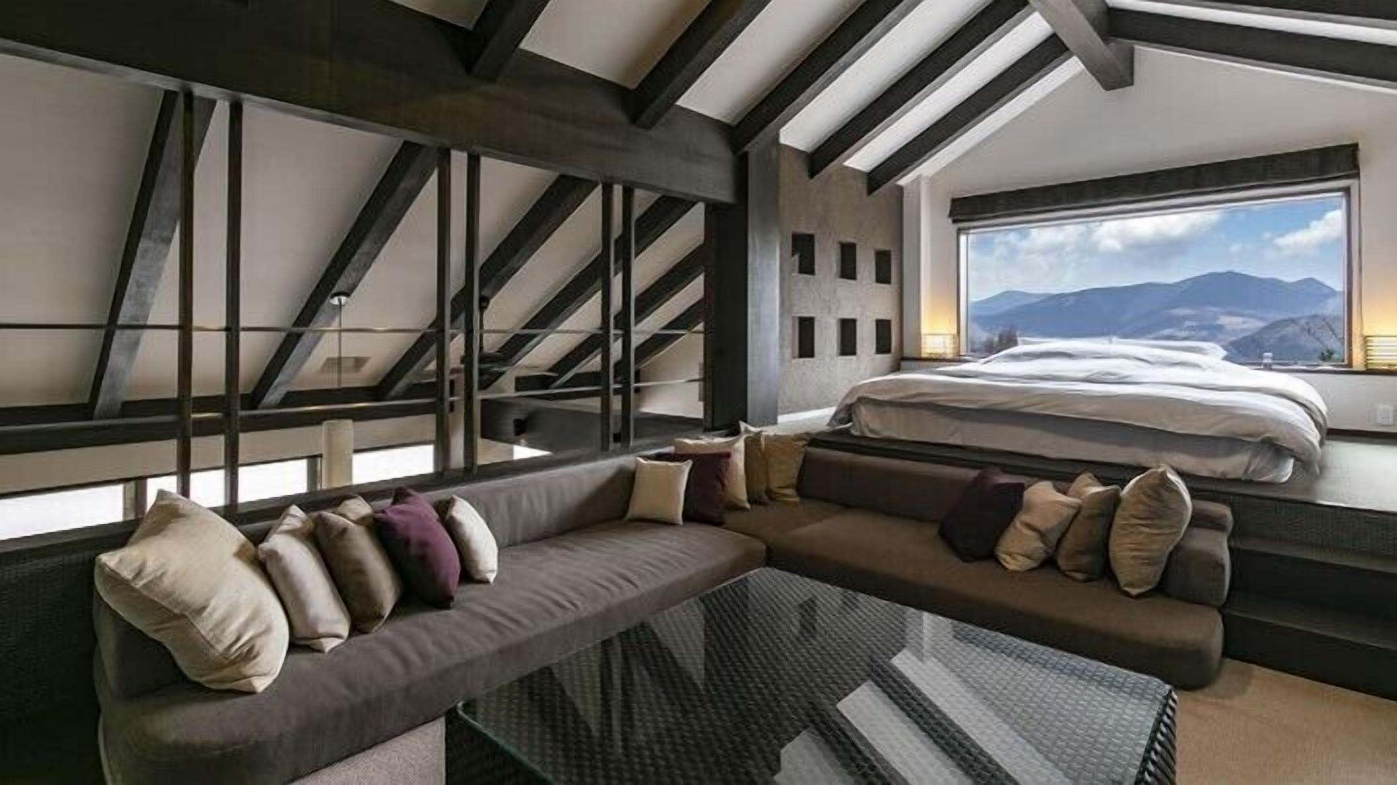 A modern interior with a bed, a sofa, and a view of mountains.