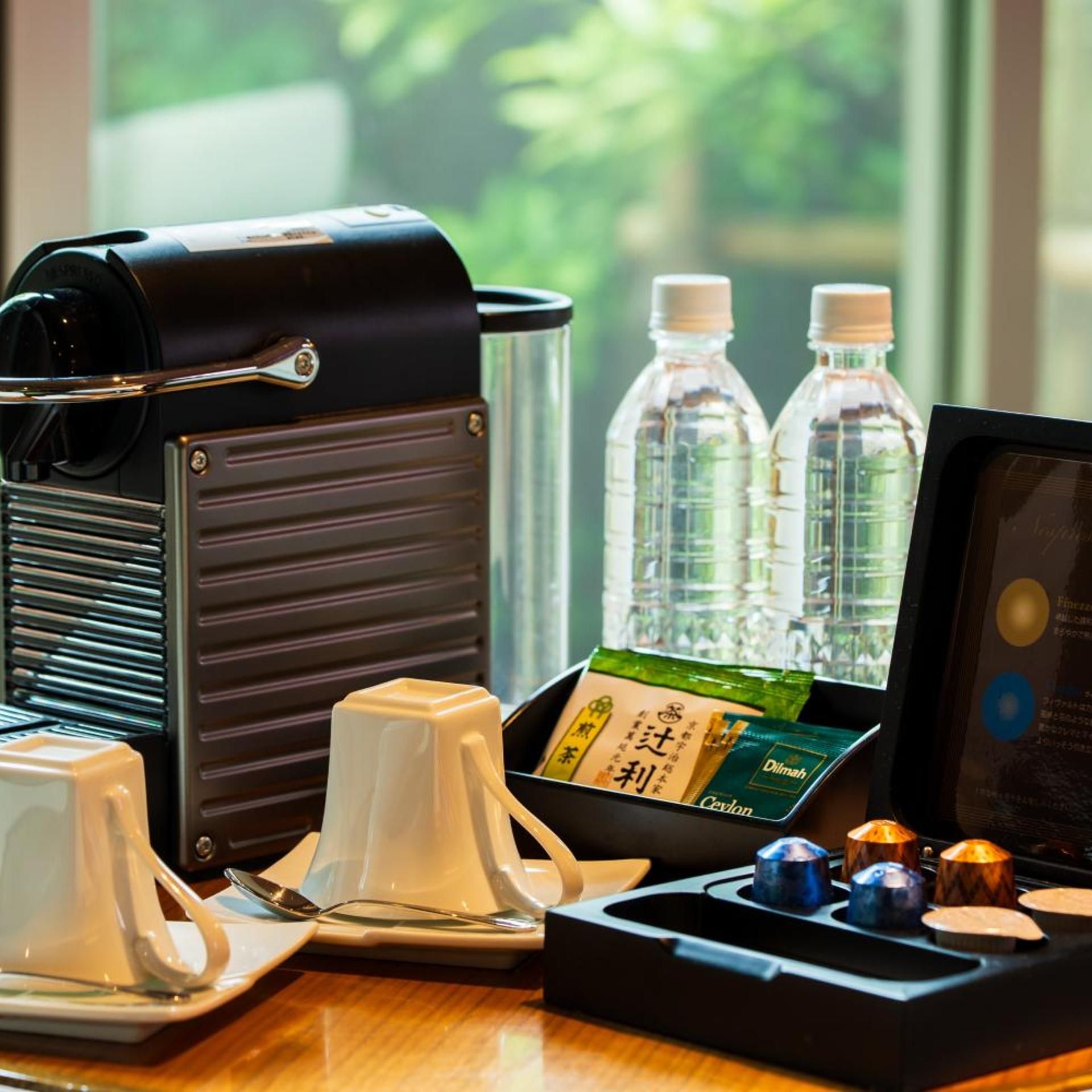 A coffee maker, two water bottles, a tea set, and a menu on a table.