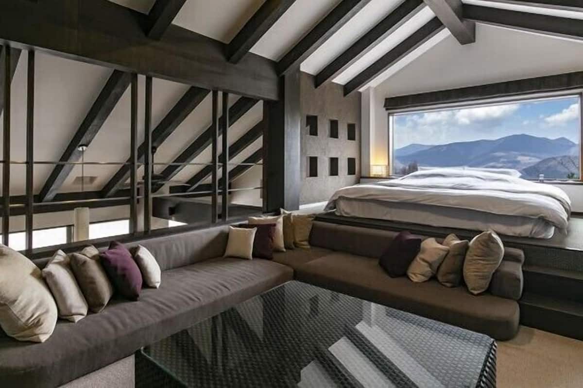 Un intérieur moderne avec un canapé, un lit et une grande fenêtre donnant sur les montagnes.