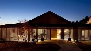 A modern building with a sloped roof, large glass windows, and a wooden deck. - Okuyado Buaisou (Yufu)