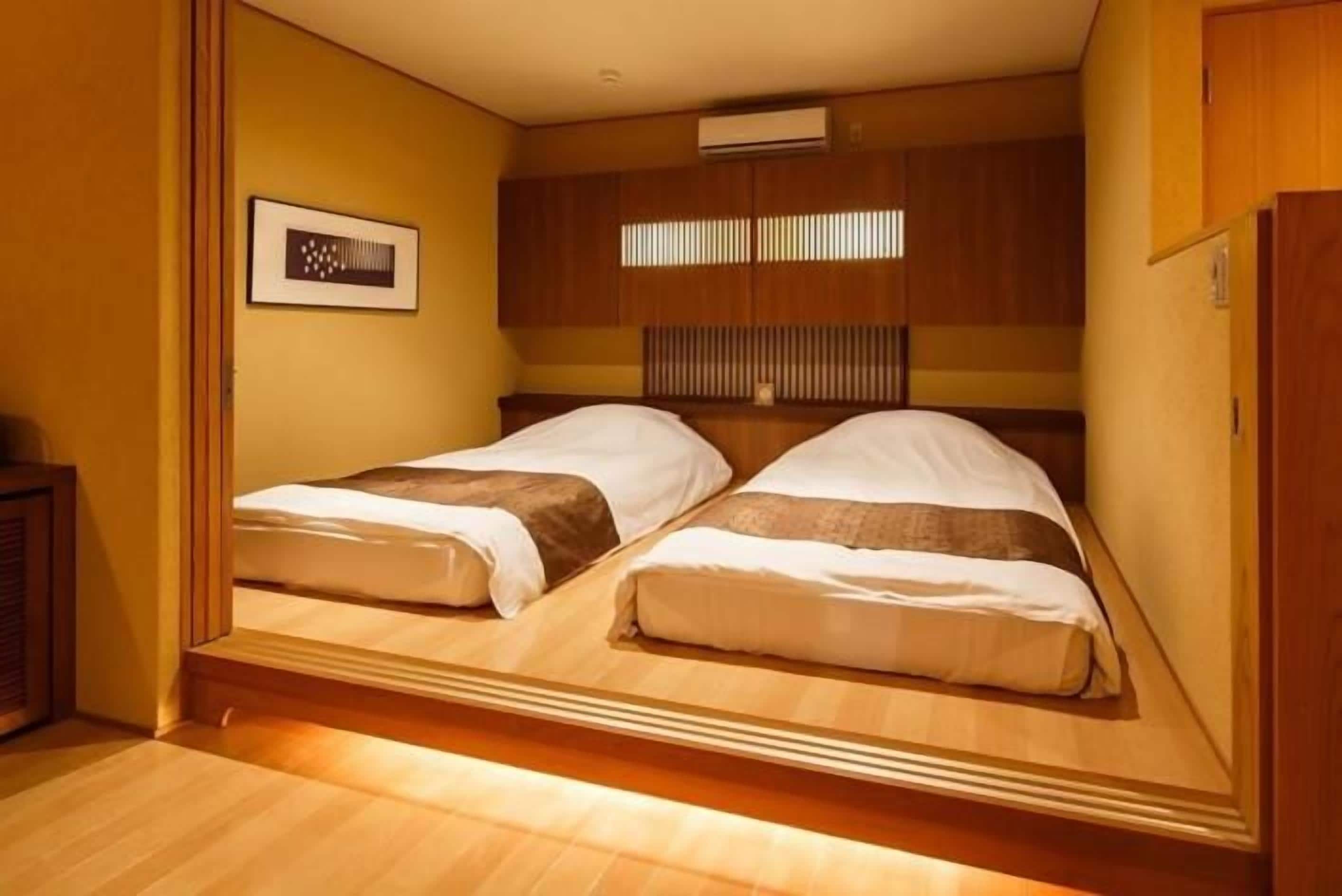 A compact room with two beds, wooden paneling, a framed picture on the wall, and a small cabinet.
