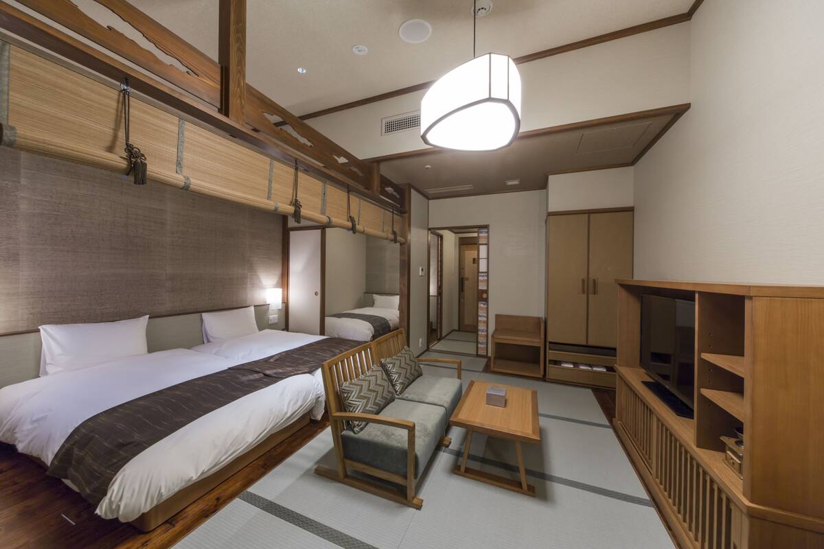 A hotel room with a large bed, a sofa, a small table, and a TV cabinet.