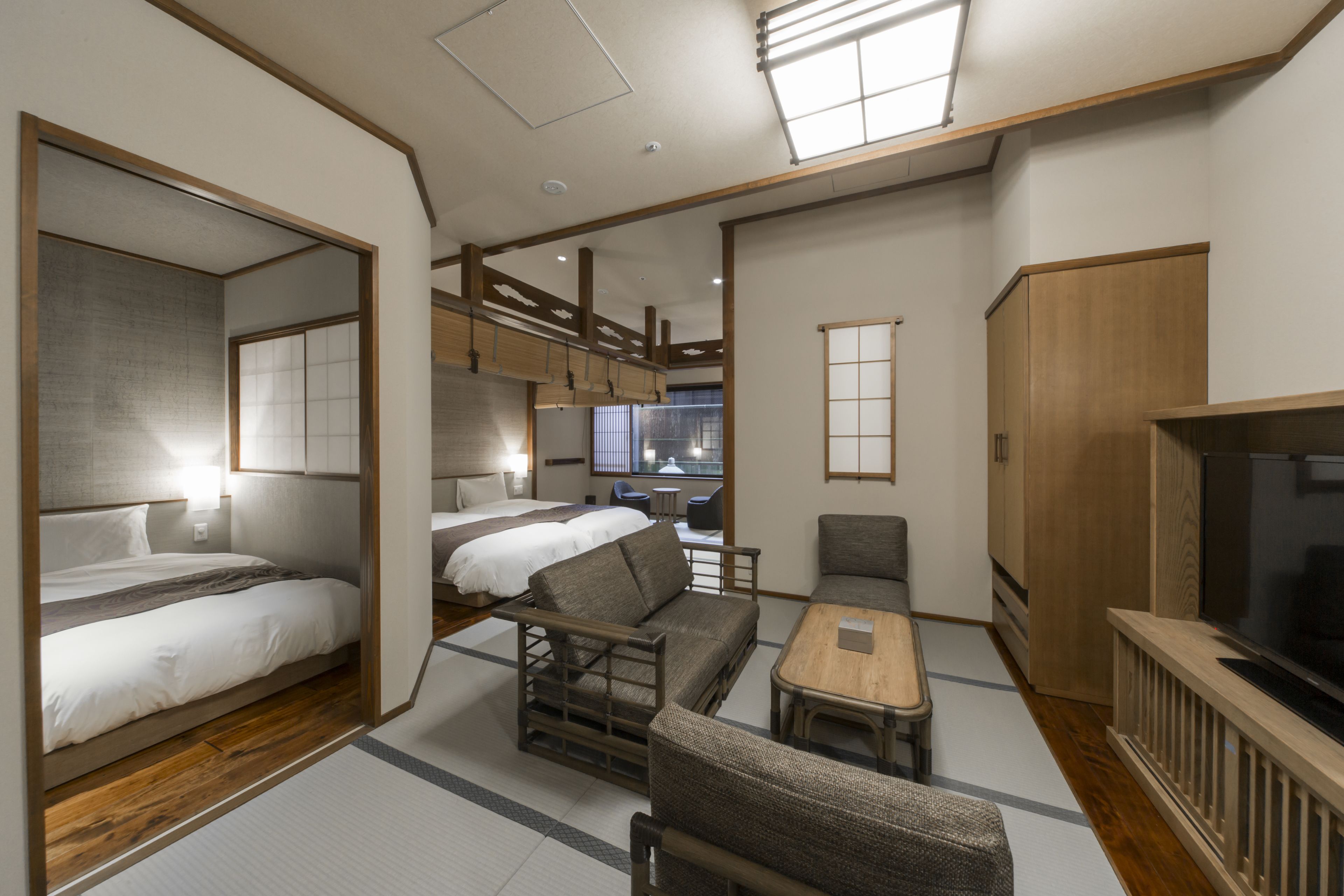 A compact hotel room with a bed, sofa, and TV.