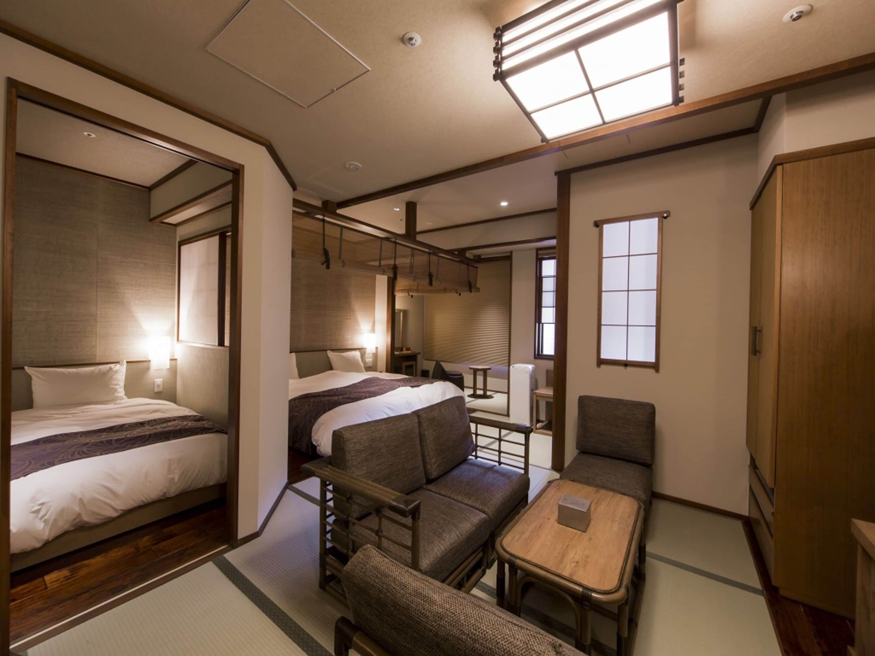 A compact hotel room with a bed, a small sofa, a table, and a wardrobe.