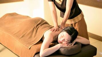 Een massagetherapiesessie in een ruimte met een massagetafel, een handdoek en een persoon die een rugmassage ontvangt.