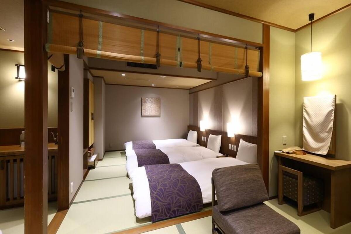 A hotel room with a large bed, a wooden ceiling, a small desk, and a chair.