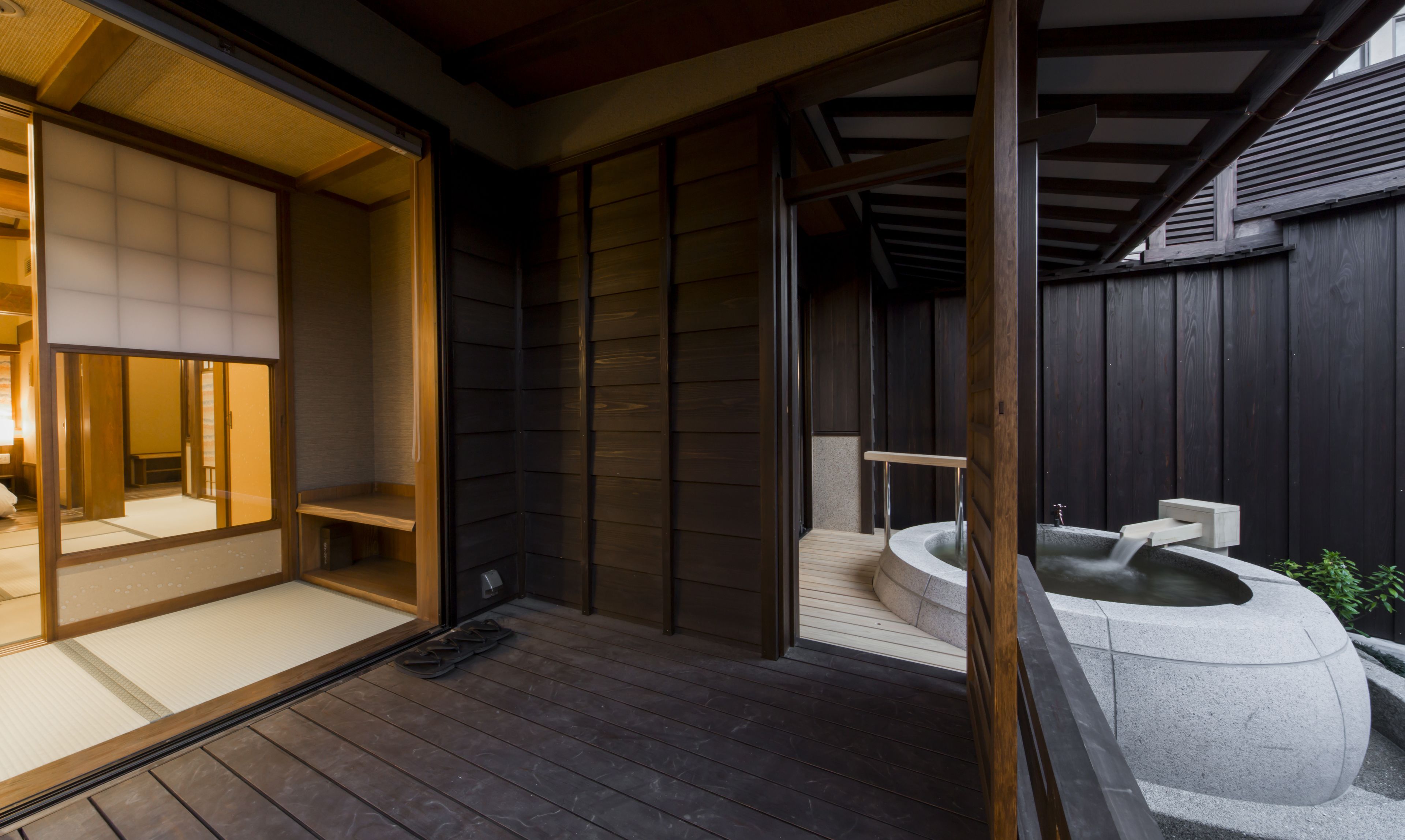 Een traditionele Japanse kamer met tatami vloeren, een schuifdeur en een stenen hottub.