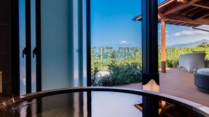 A modern interior with a large glass door leading to an outdoor patio with a view of a mountain. - Futaritowani En (Izu)