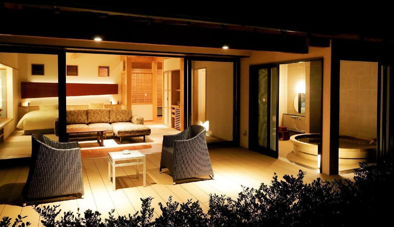 An outdoor living area with a sofa, two chairs, a table, and a built-in fireplace.