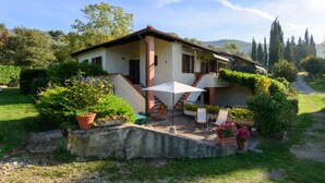 Une maison avec un patio, un espace salon extérieur et un jardin.