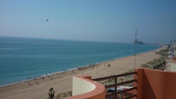 Una playa con vista despejada al mar y un horizonte urbano distante.