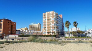 Un hotel frente al mar con varios pisos, balcones y una vista despejada de la playa.