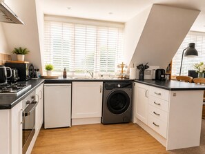Een moderne keuken met een ingebouwde wasmachine, een fornuis en een spoelbak.