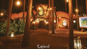 Ein rustikales Gebäude mit einer Uhr und warmer Beleuchtung, umgeben von hohen Bäumen.
