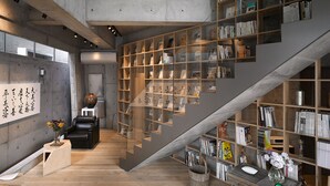 A modern interior with a staircase, bookshelves, and a minimalist design. - Mao House (Tainan)