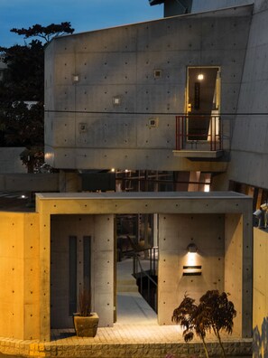 A modern building with a concrete exterior, a balcony with a railing, and a small window.