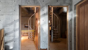 A modern interior with exposed concrete walls, wooden floors, and a spiral staircase. - Mao House (Tainan)