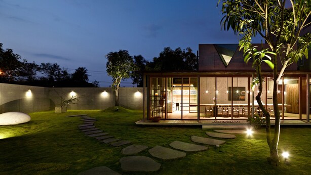 A modern house with a glass-enclosed patio, stone pathway, and outdoor seating area. - Mao House (Tainan)