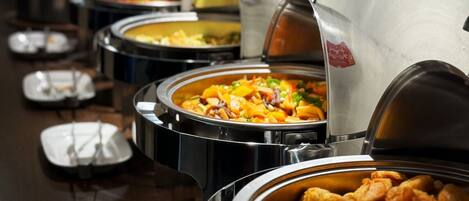 Un bufé con diversos platos en recipientes metálicos, incluyendo una sección de comida frita.