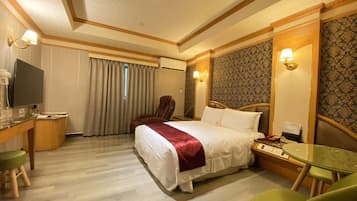 A hotel room with a bed, a desk with a computer, a chair, and a TV.