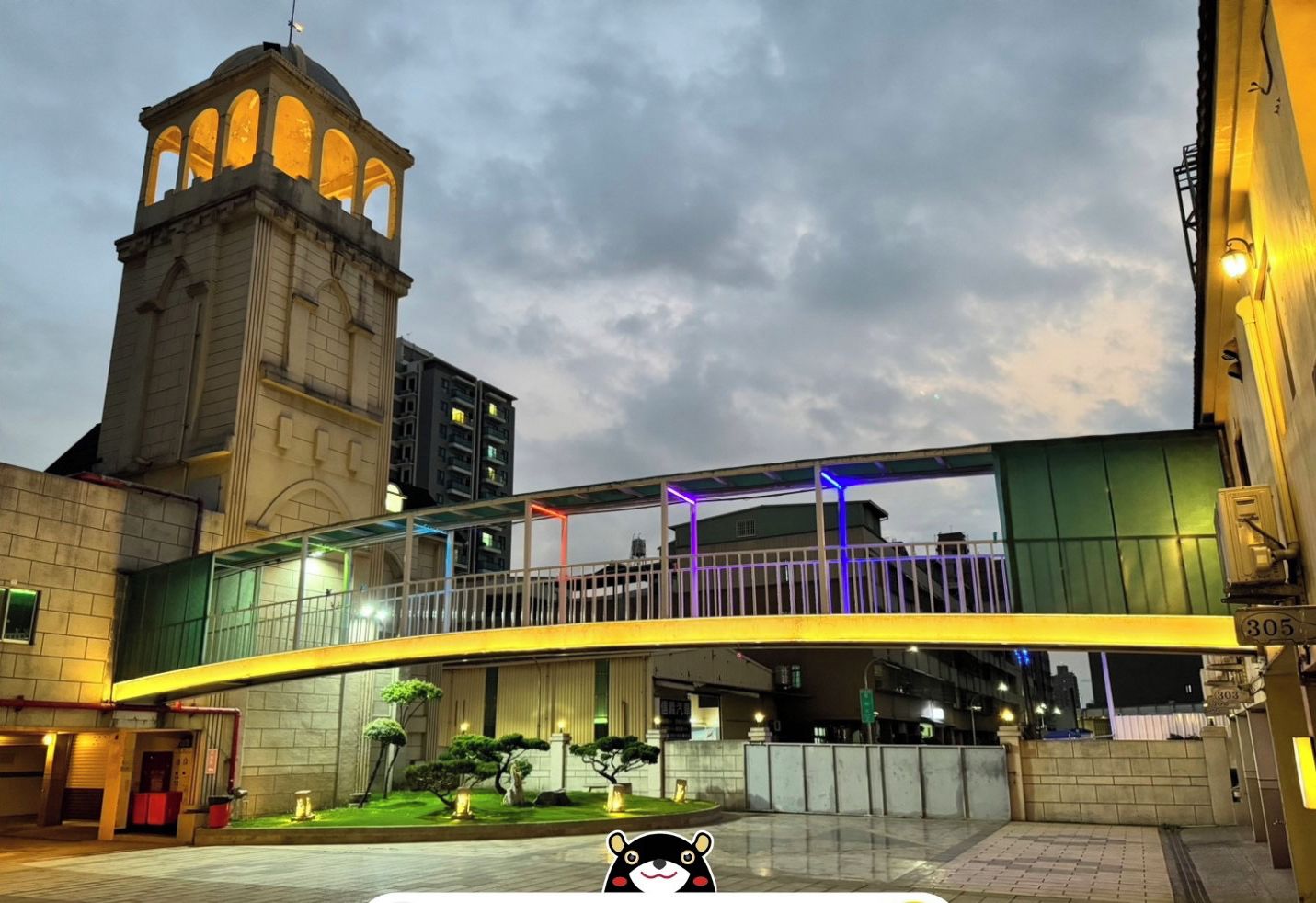 A hotel entrance with a modern bridge, a clock tower, and a registration sign.