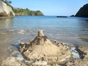 A sandy beach with a prominent sand formation in the foreground, calm water, and a distant boat. - Waterside Holiday Home with Fantastic Views (Fowey)