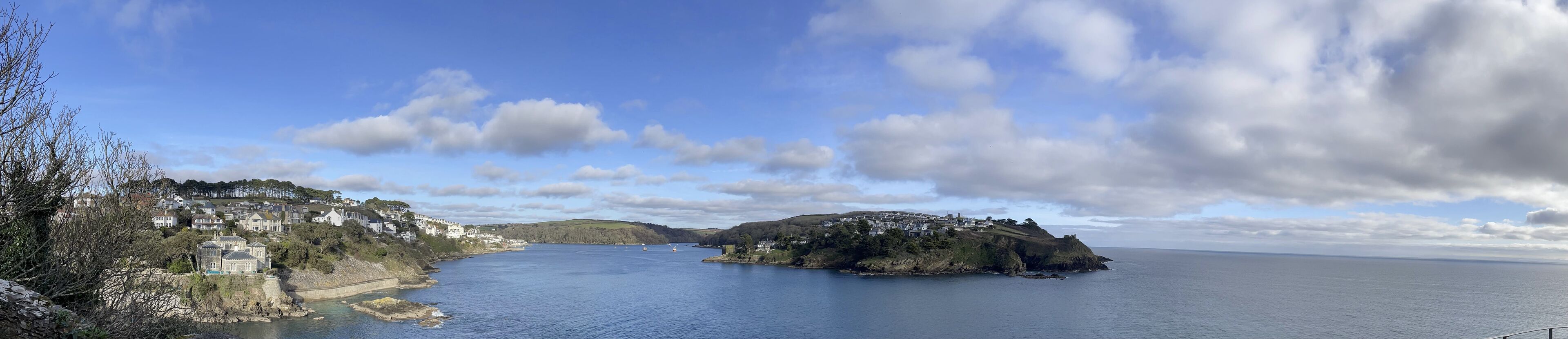 A coastal town with a prominent hill, a body of water, and a clear sky.